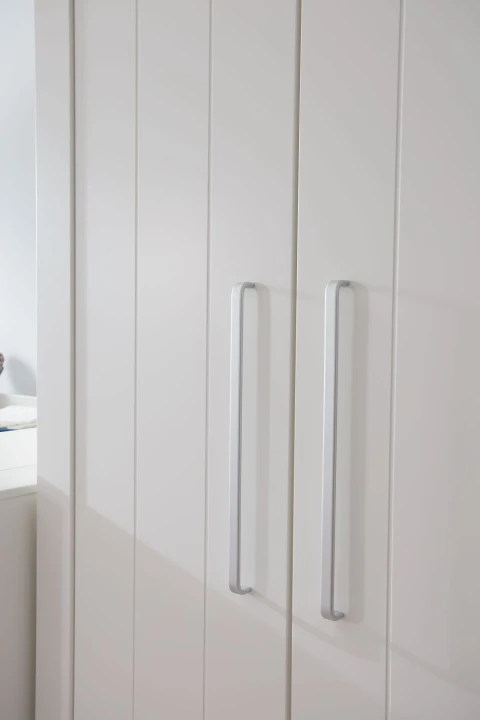 Aluminiowe uchwyty w szafie dla dziecka Calmo białej